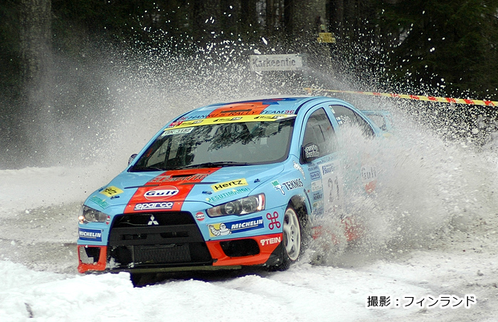 雪原を走り、しぶきが上がるラリー車